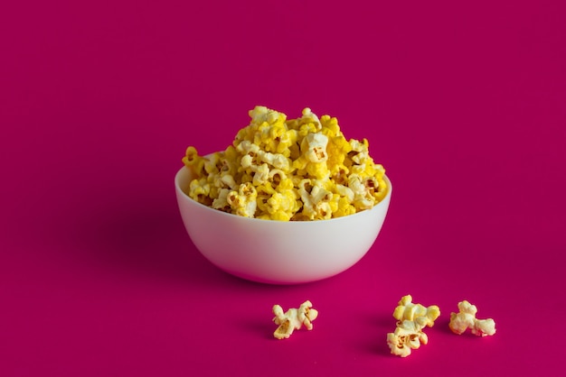 Cubo de palomitas de maíz para ver películas de cine, sobre fondo de color