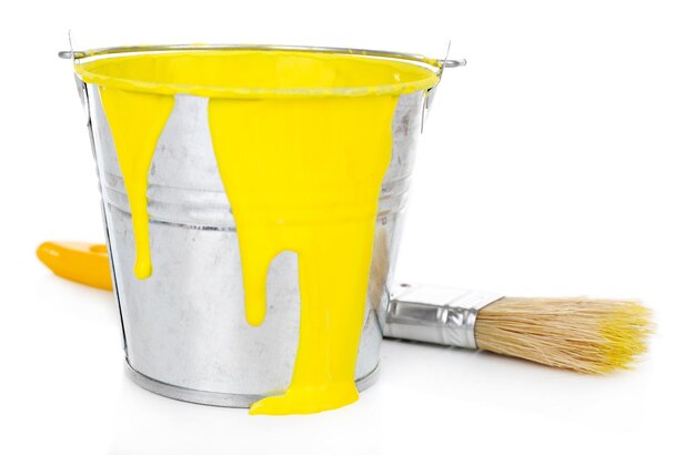 Cubo de pintura amarilla con pincel aislado en blanco