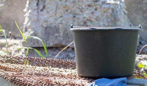 Cubo de plástico negro con agua en el jardín de verano Tanque de agua de lluvia en el jardín verano caluroso