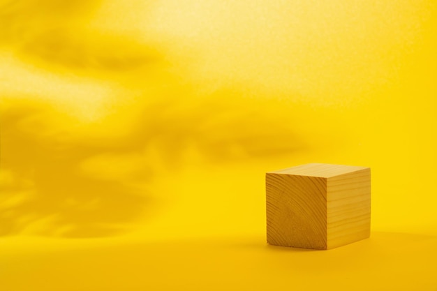 Cubo de podio de madera sobre fondo amarillo brillante