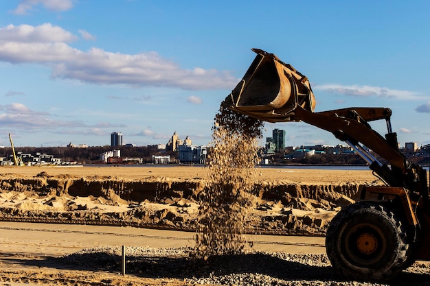 Cubo del tractor con arena en el sitio de construcción