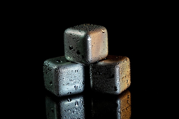 Cubos de acero inoxidable que simulan hielo para enfriar bebidas en una superficie negra con un reflejo