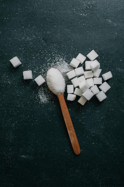 Cubos de azúcar cristalino blanco en una cuchara de madera