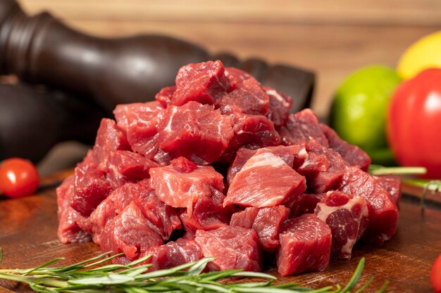 Foto cubos de carne de res o cordero crudos en cubitos de carne roja en una tabla de leña para servir carne de res cruda en cubitos en una cacerola o en un estofado