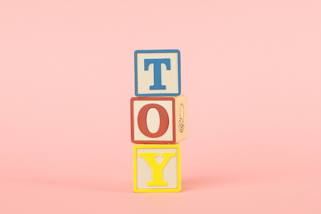 Cubos coloridos com letras com a inscrição brinquedo em um rosa