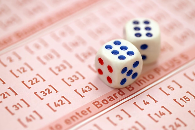 Los cubos de dados se encuentran en hojas de juego rosas con números para marcar para jugar a la lotería Concepto de juego de lotería o adicción al juego Cerrar