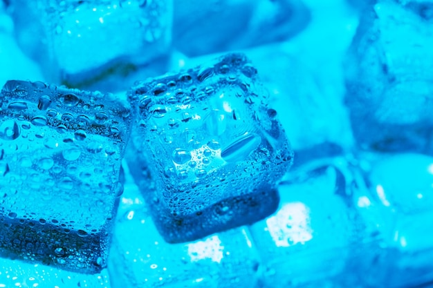 Foto cubos de gelo com gotas de água espalhadas em uma vista superior de fundo azul