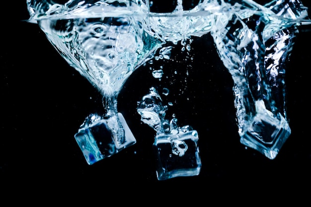 Foto cubos de gelo na água com bolhas em fundo preto