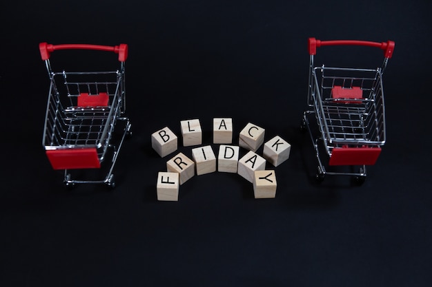 Cubos de madeira com a inscrição preta sexta-feira ao lado do carrinho de compras do supermercado