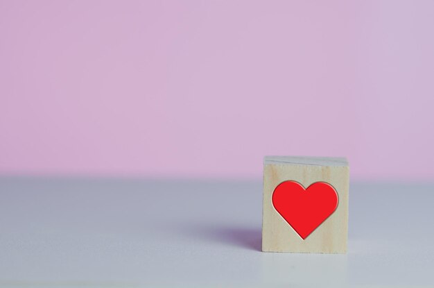 Cubos de madeira com coração símbolo de amor vermelho no fundo rosa e espaço de cópia