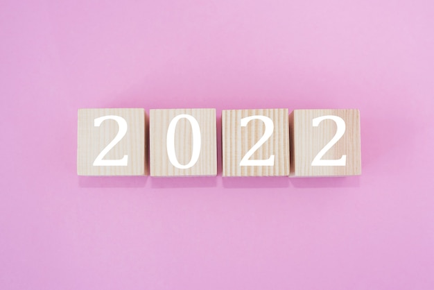 Cubos de madeira com o texto 2022 em fundo rosa, início do novo ano.