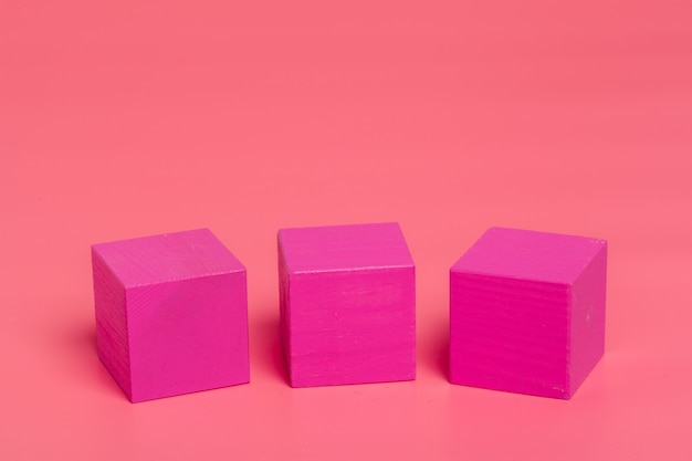 Cubos de madeira rosa sobre fundo colorido rosa