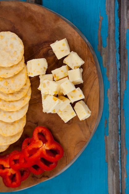 Foto cubos de queijo, pimento e biscoitos na placa de madeira