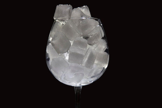 cubos de hielo congelados en una copa de vino vacía sobre un fondo oscuro