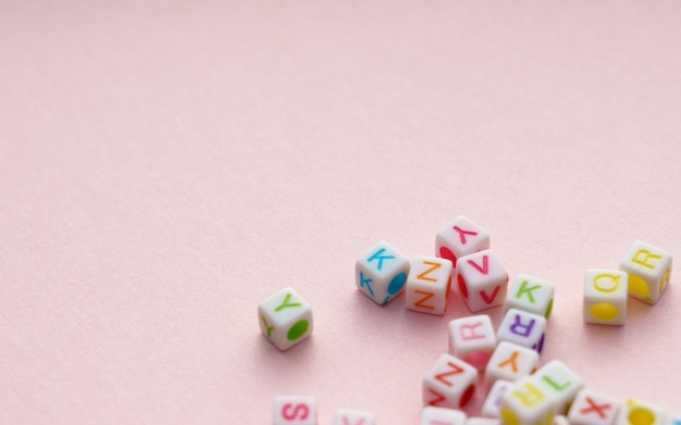 Cubos de letras del alfabeto colorido sobre fondo rosa
