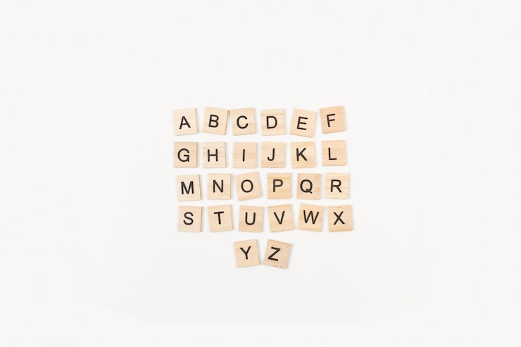 Cubos de letras de madera en orden alfabético sobre un fondo blanco.