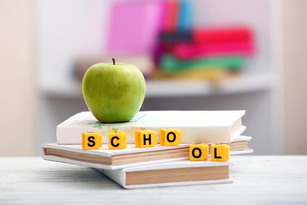 Cubos de libros y manzana en el primer plano de la mesa