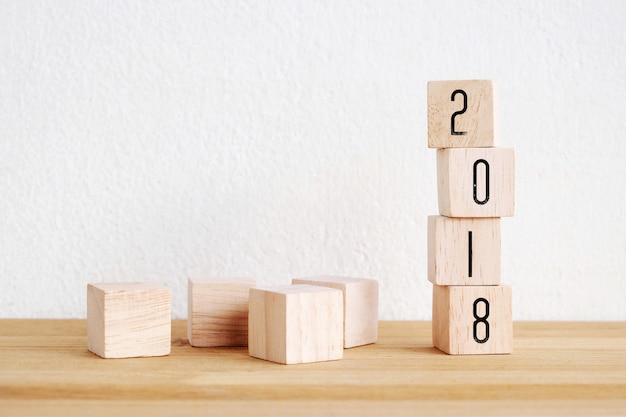 Cubos de madera con 2018 en madera de perspectiva sobre la mesa y fondo de pared blanca