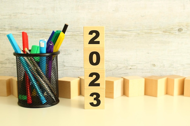 Cubos de madera apilados con letras 2023 sobre una mesa de trabajo blanca sobre un fondo gris texturizado