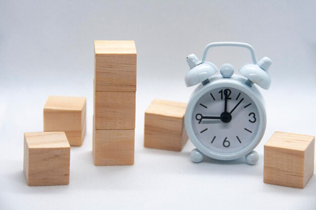 Cubos de madera en blanco y despertador blanco sobre fondo blanco con espacio personalizable para texto o ideas