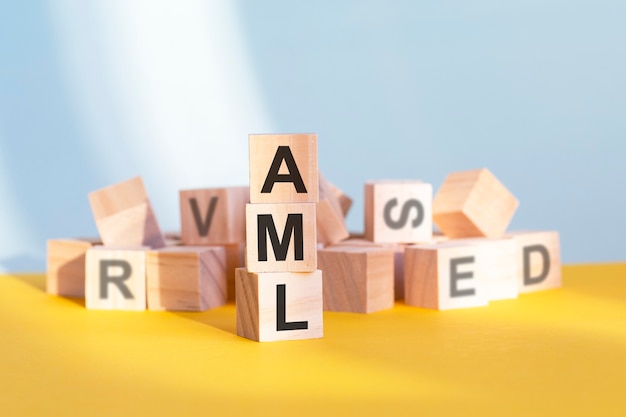 Cubos de madera con letras AML dispuestas en una pirámide vertical, fondo amarillo