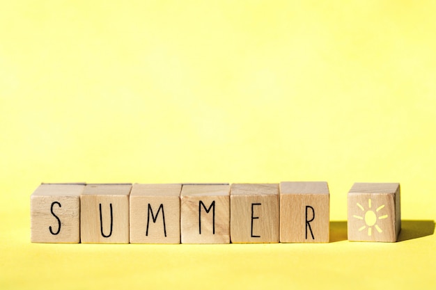 Cubos de madera con la palabra verano sobre fondo amarillo, colorido brillante concepto de verano. Alegre