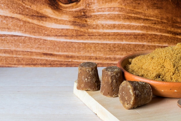 Cubos y Panela en polvo o caña de azúcar dulce en una tabla de cortar con fondo de madera comida típica de Colombia