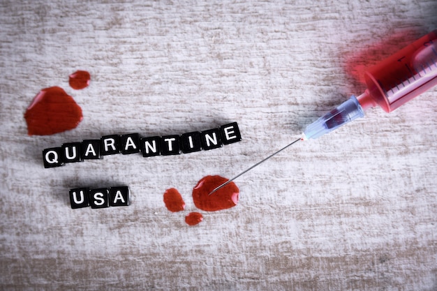 Cubos de texto con la inscripción "Quarantine USA" y una jeringa. Concepto de brote de enfermedad por coronavirus (COVID-19) en Estados Unidos