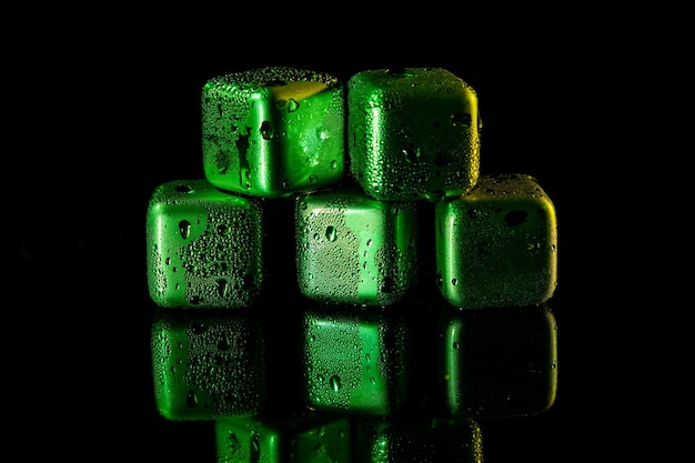 Cubos verdes de acero inoxidable que simulan hielo para enfriar bebidas en una superficie negra con un reflejo