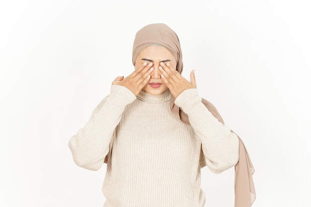 Cubriendo los ojos de la hermosa mujer asiática vistiendo Hijab aislado sobre fondo blanco.