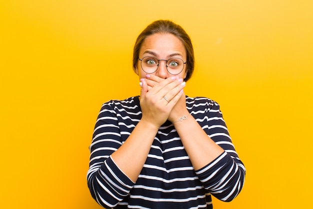 cubriéndose la boca con las manos con una expresión sorprendida, sorprendida, guardando un secreto o diciendo oops