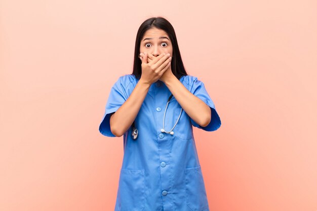 cubriéndose la boca con las manos con una expresión de sorpresa y sorpresa, guardando un secreto