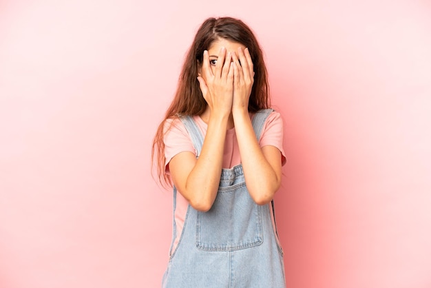 Cubrirse la cara con las manos asomándose entre los dedos con expresión sorprendida y mirando hacia un lado