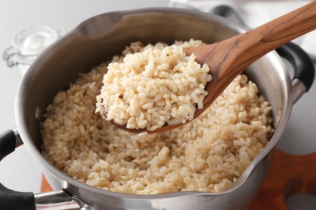 Cuchara con arroz integral preparado sobre una cacerola