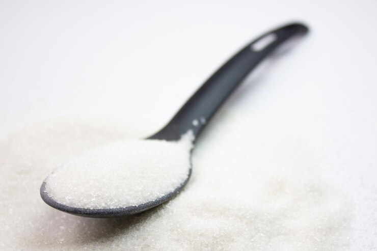 Foto cuchara de azúcar ingrediente aditivo de azúcar sobre fondo blanco
