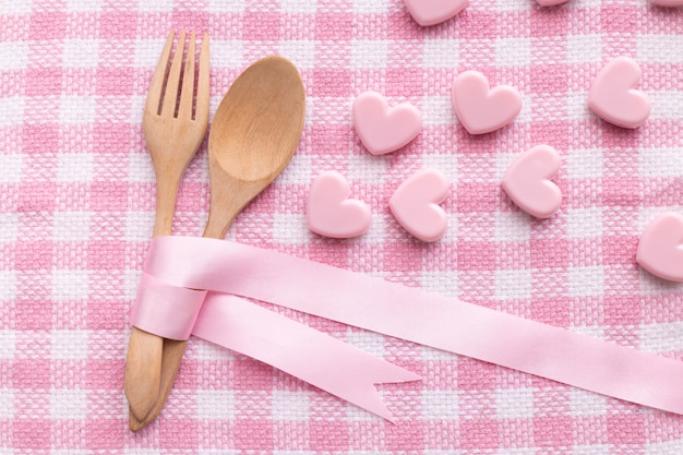 Cuchara y bifurcación en el fondo rosado del mantel, fondo del día de tarjetas del día de San Valentín.