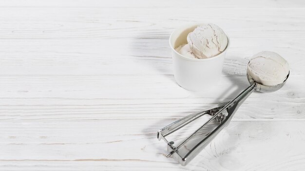 Foto cuchara con bola de helado cerca de la taza