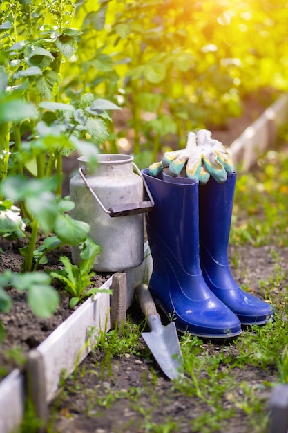 Foto cuchara de botas de goma y herramientas después de la jardinería entre camas