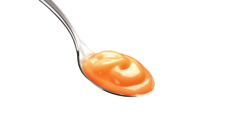 Una cuchara con una cuchara con líquido naranja