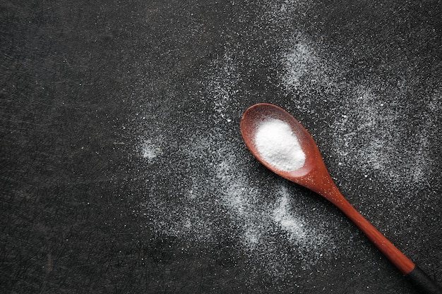 Cuchara de edulcorante blanco sobre un fondo negro