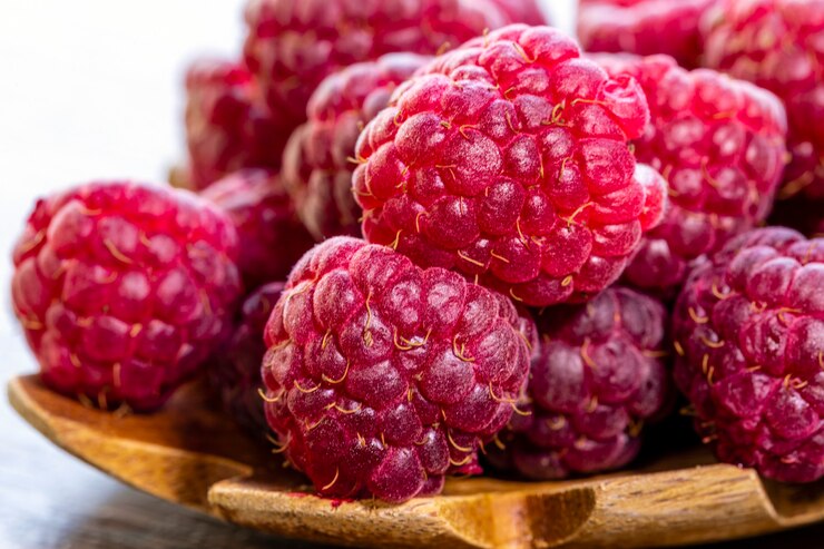 Foto cuchara con frambuesa y cuenco con mermelada de frambuesa sobre fondo de madera,