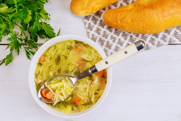 Cuchara llena de sopa de pollo con fideos