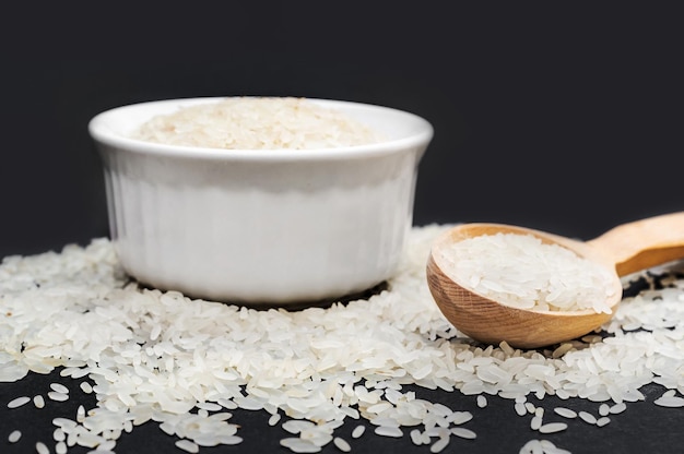 Cuchara de madera con arroz y tazón de arroz en negro