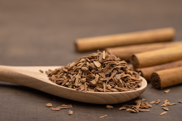 Cuchara de madera con canela triturada rollos de canela sobre un fondo de madera marrón Espacio de copia de primer plano