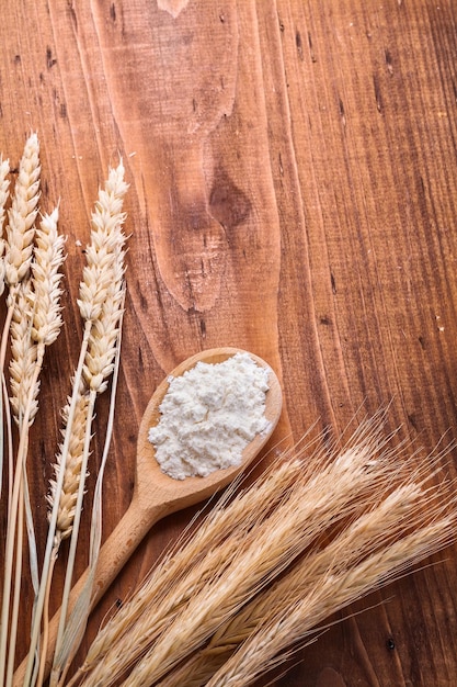 Cuchara de madera clásica con espigas de trigo de harina natural blanca en concepto de comida y bebida de tablero vintage