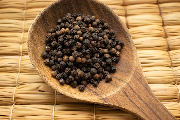 Cuchara de madera grande con granos de pimienta negra