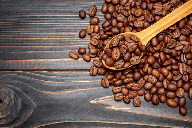 Cuchara de madera de granos de café tostados en la mesa