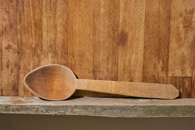 Cuchara de madera hecha a mano en un estante de cocina de madera.