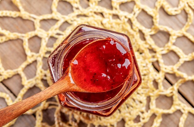 Foto cuchara de madera llena de mermelada de fresa