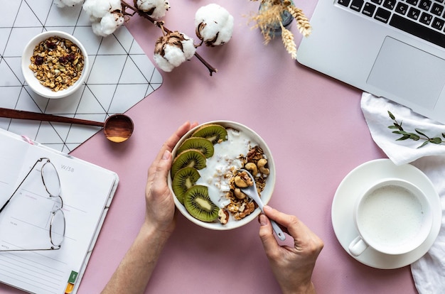 Cuchara de mano femenina sobre concepto de desayuno saludable en el fondo de la mesa de trabajo